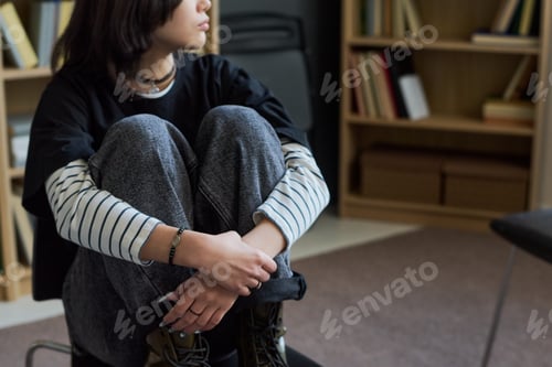 Preview: Teenage Girl Sitting Cross Legged during Group Therapy Session Indoors