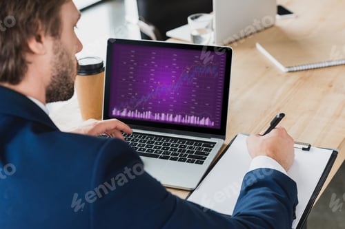 Preview: cropped shot of businessman taking notes on clipboard and using laptop with business charts on