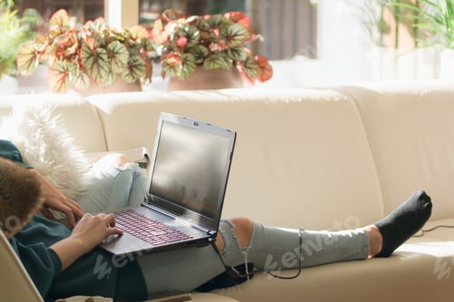 Preview: Generation x woman sitting comfortably on the couch and working on her laptop from home.
