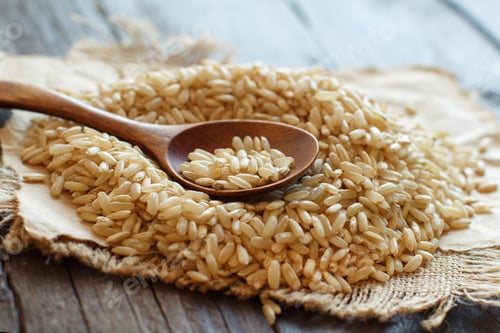 Preview: Pile of Brown rice with a wooden spoon