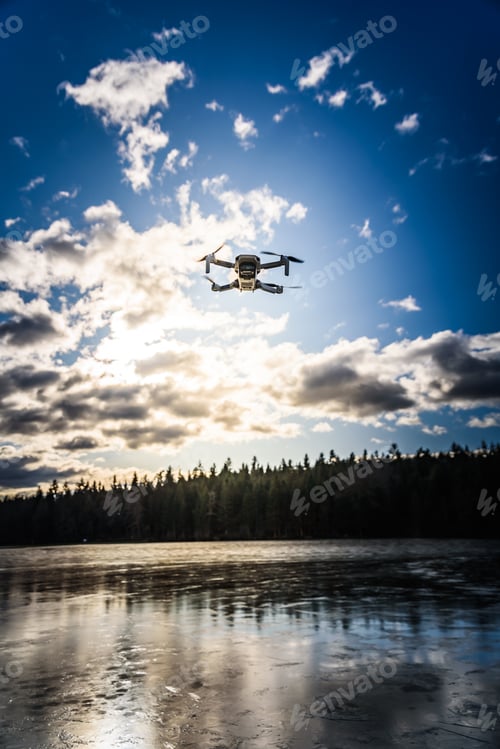 Preview: Graz, Austria - December 29 2019. DJI Mavic Mini drone flying in the countryside above frozen lake