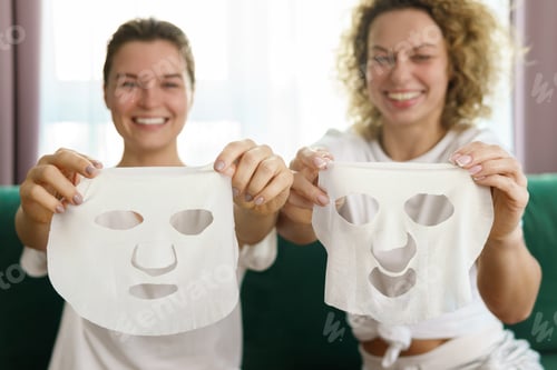 Preview: Two beautiful and cheerful girls with a sheet masks for skin hydration