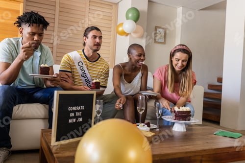 Visualização: Comemorando um novo emprego, amigos diversos saboreando bolo e champanhe em casa