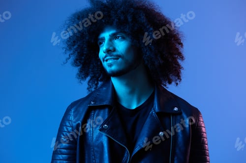 Preview: Portrait of fashion man with curly hair on blue background multinational, colored light, black