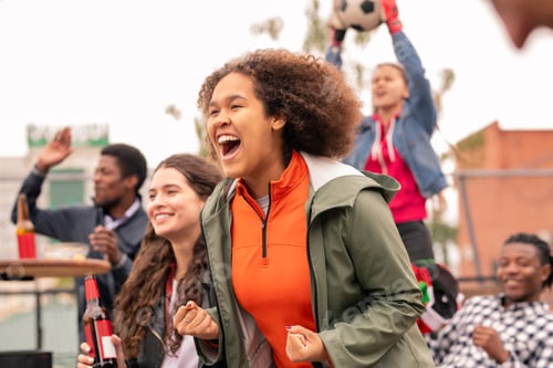 Preview: Ecstatic intercultural friends cheering for their football team after goal