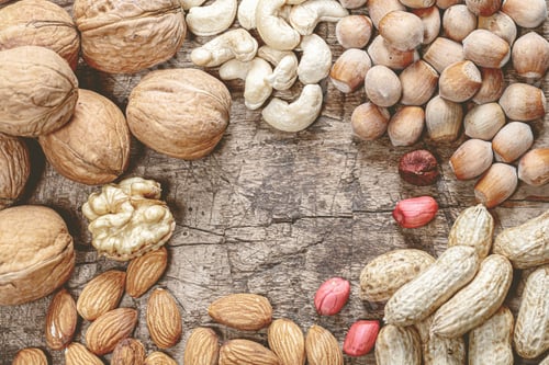 Preview: multiple nuts on wooden board in different flavors and sizes shown