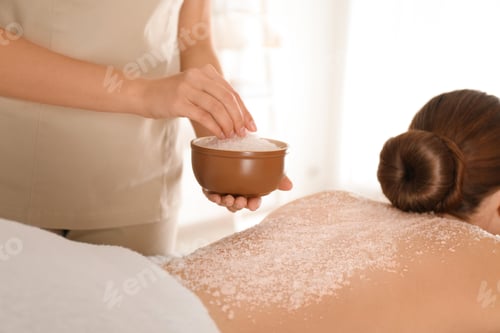 Preview: Young woman having body scrubbing procedure with sea salt in spa salon, closeup