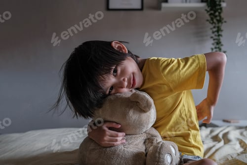Preview: Beautiful kid on bed hugging teddy bear with happy smile on her face