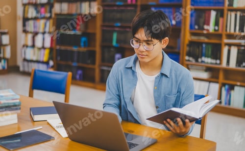 Preview: Male college students are working on laptops and searching for books to study,