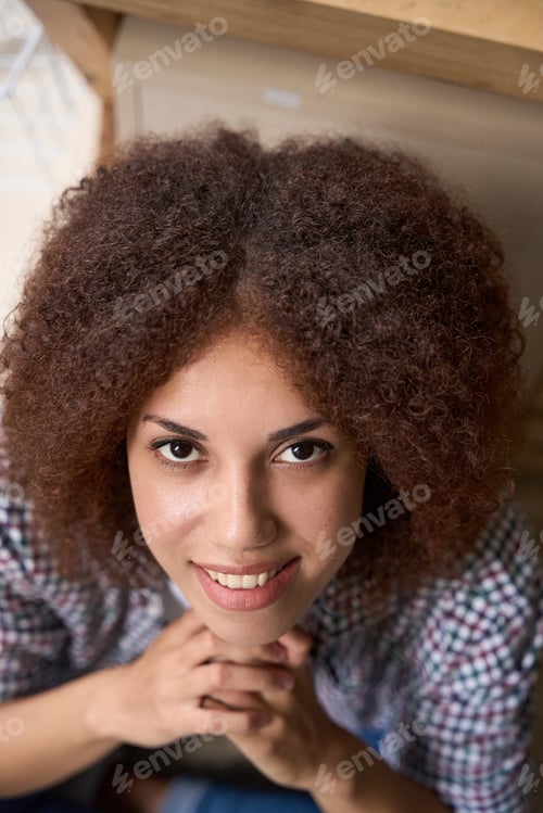 Preview: Smiling young curly woman looking into camera