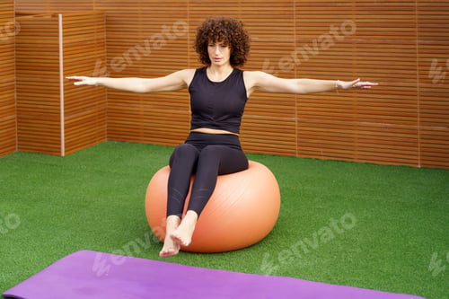 Preview: Fitness Exercise A woman expertly balancing on a stability ball within a gym setting