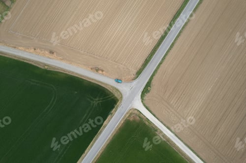Preview: Lonely car parked at crossroads of countryside roads and cultivated fields