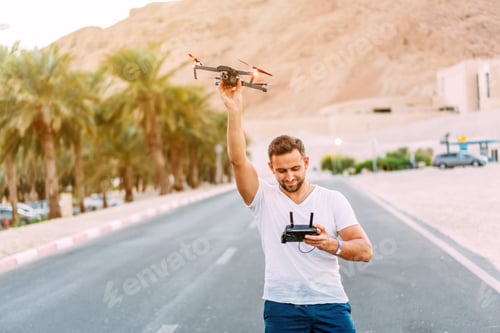 Preview: Young man holding drone before flight at nature