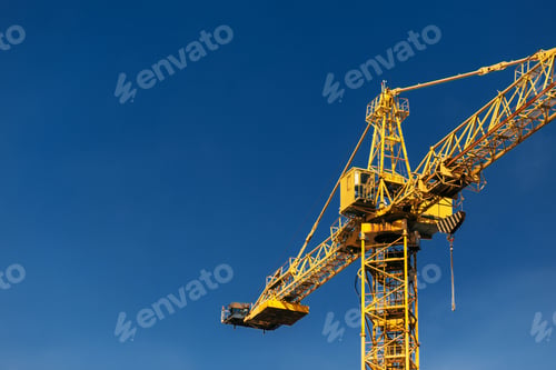 Preview: Construction crane tower in sun light beams on background of blue sky