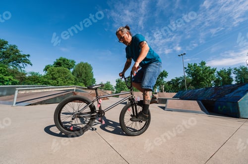 Preview: A middle-aged urban tattooed guy is training an extreme sport in a skate park.