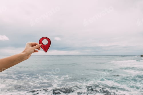 Preview: cropped view of woman holding paper as location sign near mediterranean sea