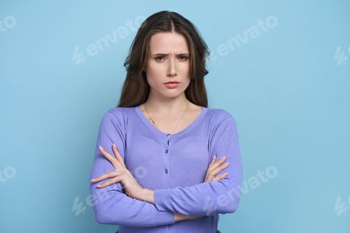 Vista previa: Isolated portrait on blue background of perplexed confuded woman with arms folded