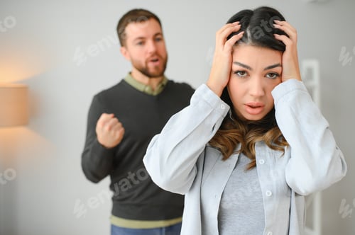 Preview: Emotional man gesturing and shouting at his wife, young couple having quarrel at home.