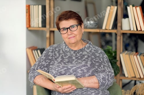 Preview: Beautiful old woman in casual clothes reading on couch at home.