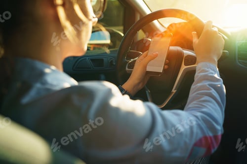 Preview: Happy woman uses a navigator in a smartphone while driving a car