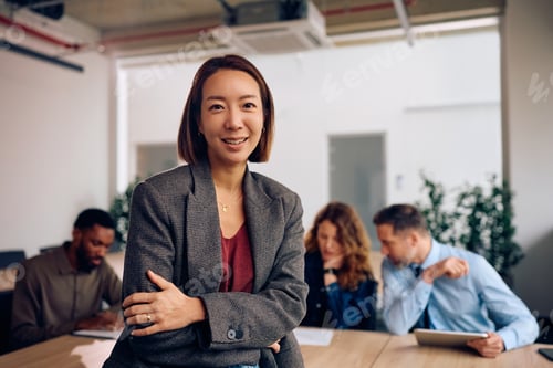 Preview: Happy Korean CEO having a meeting with her business team and looking at camera.