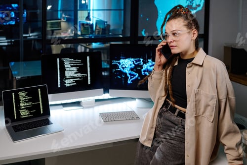 Preview: Confident female programmer talking to colleague on smartphone