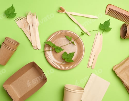 Preview: Disposable paper utensils from brown craft paper and recycled materials on a green background