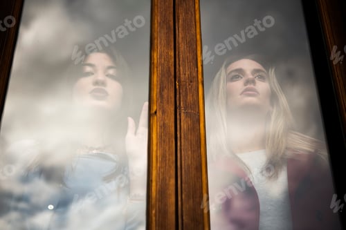 Preview: Two women gaze thoughtfully through a window, reflections and dreams merging.