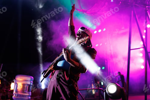 Preview: Clown entertains guests in the circus arena in the light of spotlights and smoke, plays the guitar.