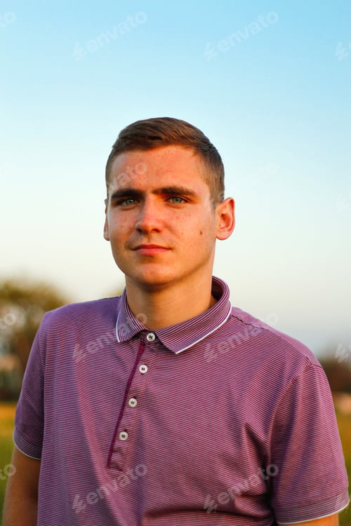 Preview: Young people.Portrait of serious young brunette man in purple polo shirt standing outdoor on nature