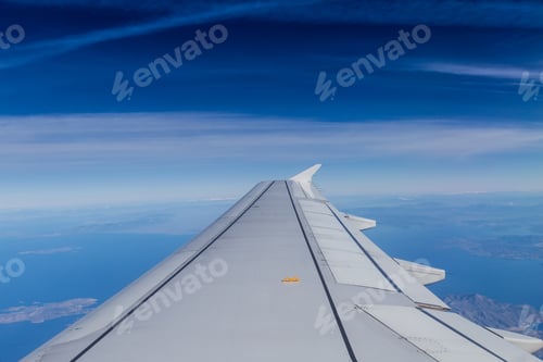 Preview: Blue horizon with soft clouds, aerial shot from airplane, with wing visible