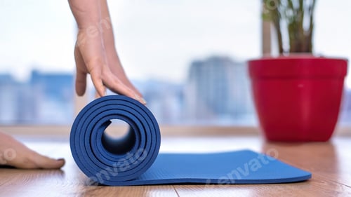 Preview: Yoga Mat Being Rolled on Wooden Floor
