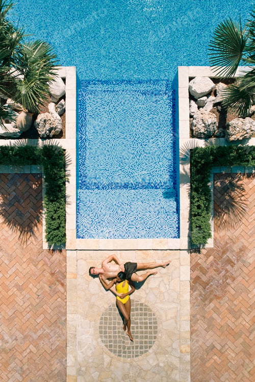 Preview: Woman laid her head on man stomach while lying by the pool. Top view