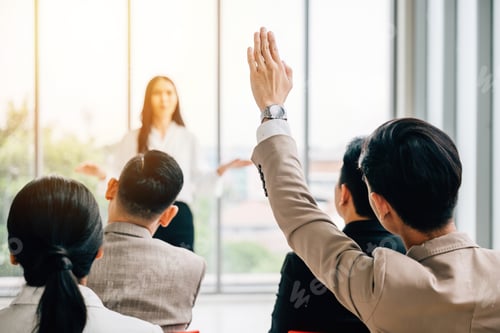 Preview: In a seminar classroom, a large group actively participates in the discussion, with raised hands