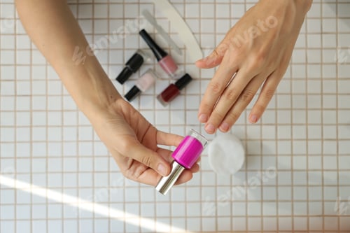Preview: lady chooses color of nail polish. woman's hand and nail polish on table background.