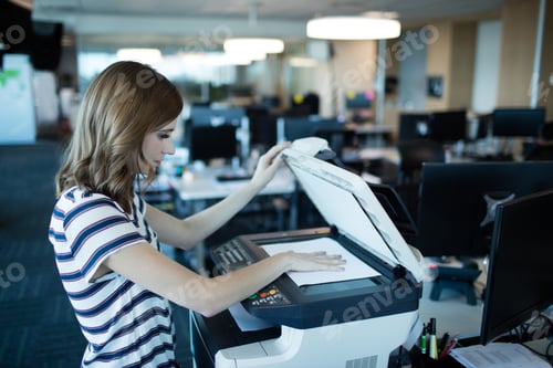 Preview: Businesswoman using copy machine in office
