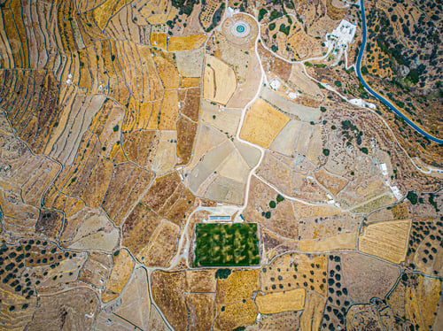 Preview: Aerial view on a green football field during drought on sifnos island, Greece