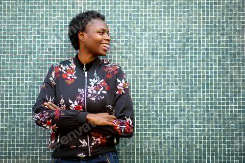 Preview: African woman with arms crossed smiling against green wall