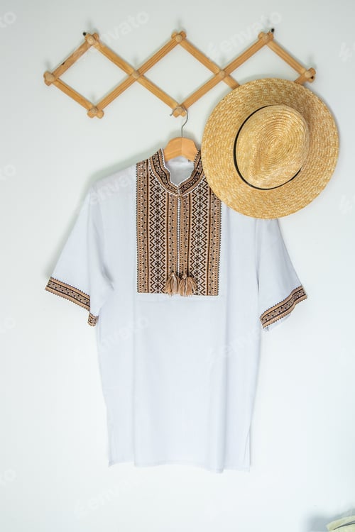 Preview: Ukrainian clothes embroidered shirt. Brown beige and white black threads background. Straw hat