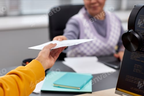 Preview: Close up of two young people handing document across table