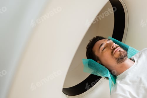 Preview: high angle view of brunette man lying during scanning on computed tomography machine