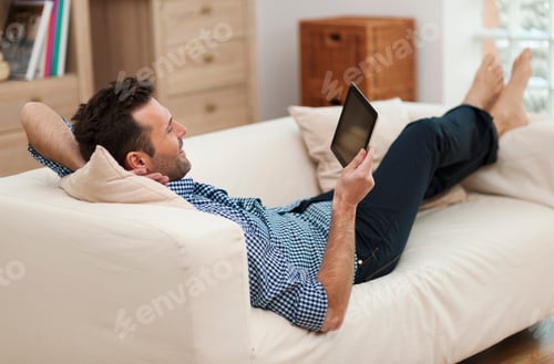 Preview: Man relaxing with digital tablet at home