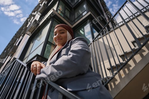 Aperçu: Arab woman posing on the stairs against the backdrop of a high-rise building
