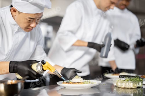 Preview: Group of cooks finishing main courses while working together in the kitchen