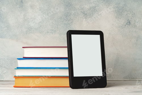 Preview: Digital tablet with a stack of books on gray background