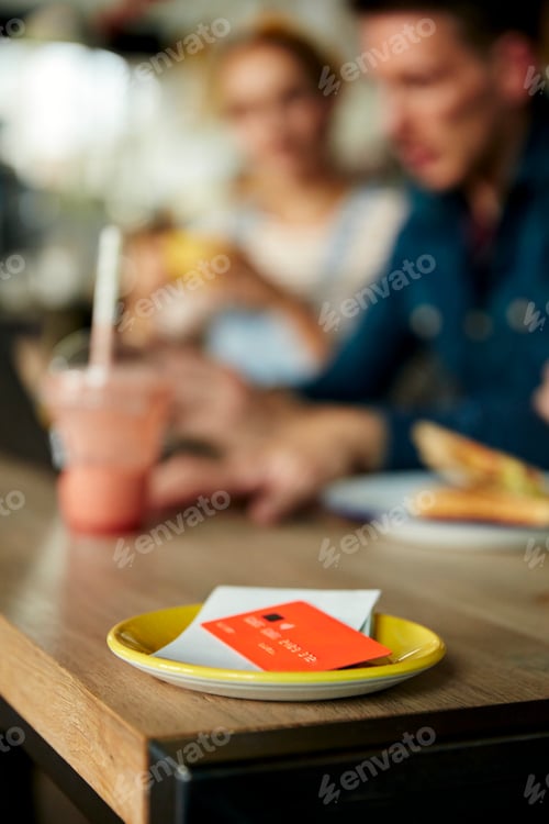 Preview: People at a cafe table, a saucer with till receipt and credit card.