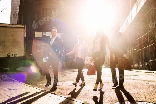 Preview: Business people walking on street against buildings during sunny day