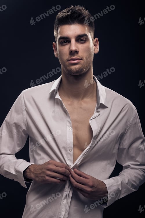 Preview: One Young Man Buttoning, White Shirt, Looking At Camera, Black Background