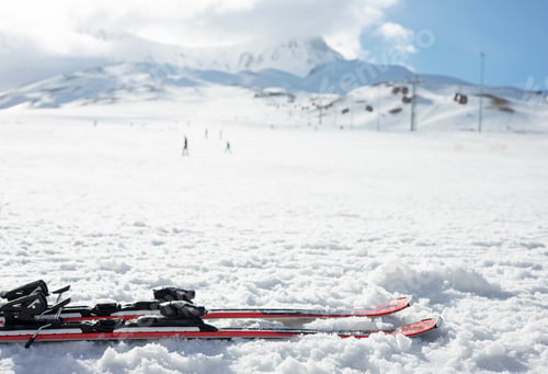 Preview: Mountain skis and ski sticks on bright alpine snow on background of mountain slope