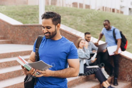 Preview: Smiling Indian Student with Books on College Campus Steps Enjoying Study Time